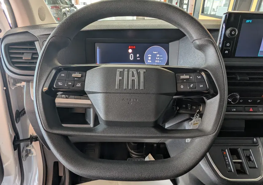 Vue rapprochée du volant noir du Fiat Scudo Fourgon XL 145 EAT8 2024 avec tableau de bord digital et commandes intégrées.