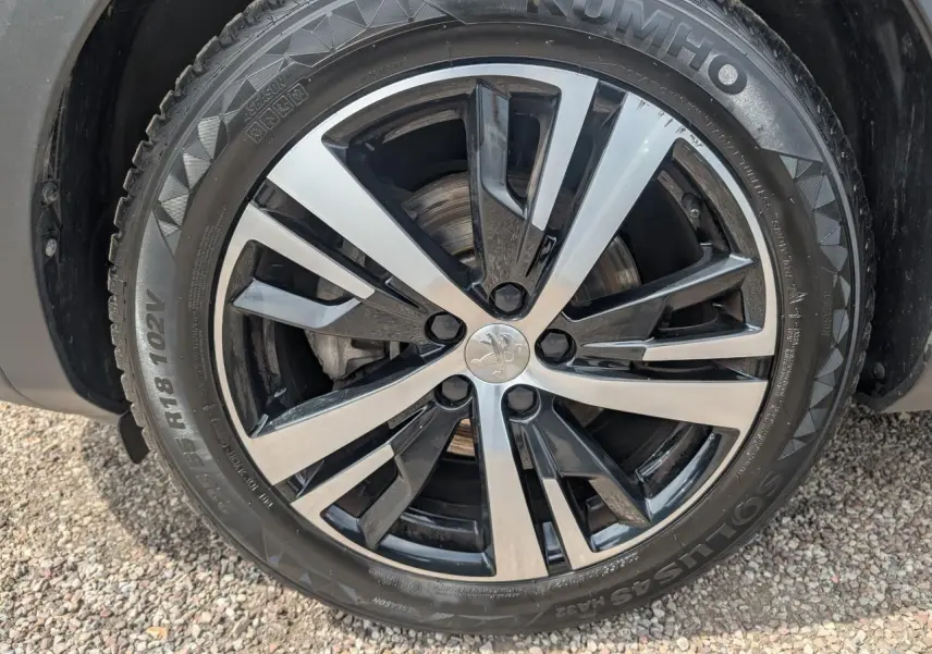 Gros plan sur la jante alliage 18 pouces bi-ton noir et argent du Peugeot 5008 gris 2023 version GT.