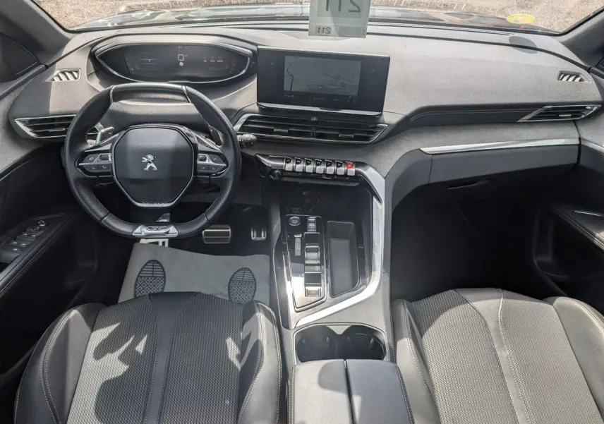 Vue intérieure avant du Peugeot 5008 GT 2023, tableau de bord noir avec écran tactile et volant compact cuir.