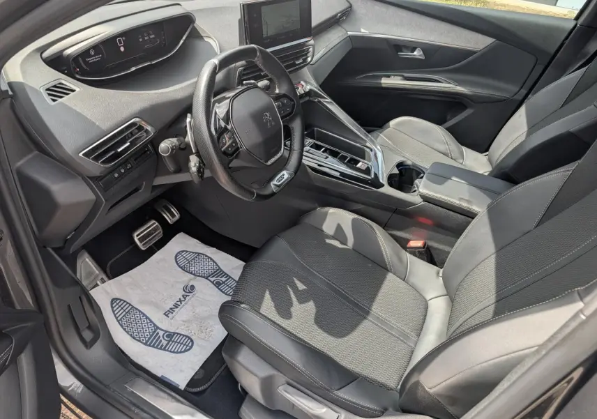 Vue intérieure côté conducteur du Peugeot 5008 gris 2023, mettant en valeur le volant compact GT et la console centrale moderne.