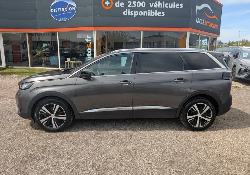 Peugeot 5008 gris métallisé vue de profil côté gauche, avec jantes bi-ton et vitres arrière surteintées.