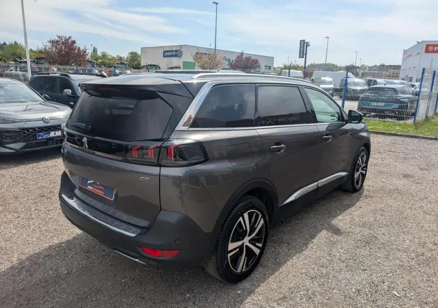 Peugeot 5008 GT gris métallisé vue 3/4 arrière droit, feux arrière LED 3D et jantes alliage bi-ton visibles.