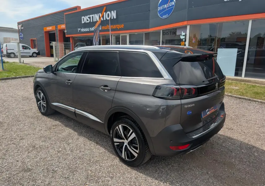 Vue 3/4 arrière droit d’un Peugeot 5008 gris métallisé avec jantes bi-ton et vitres arrière surteintées.
