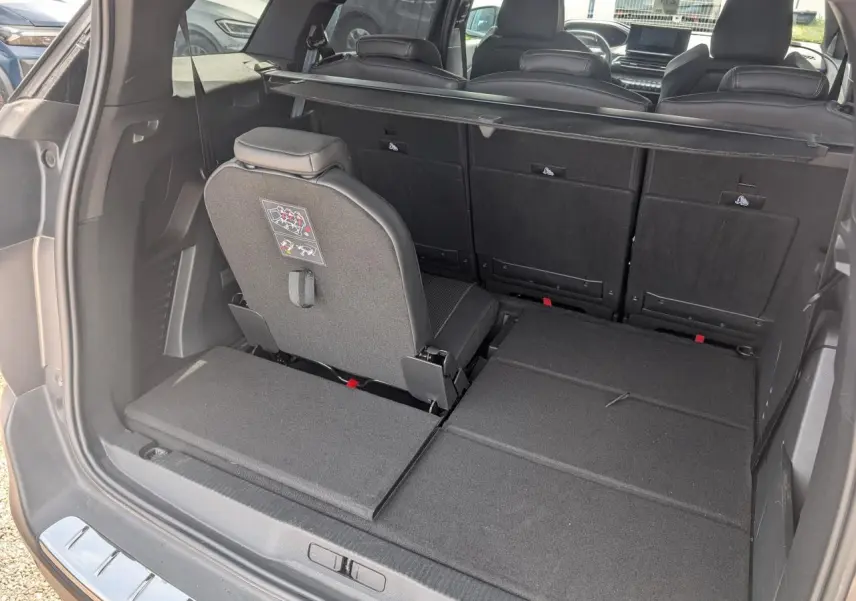 Vue arrière du coffre du Peugeot 5008 gris 2023 avec siège arrière droit relevé et banquette rabattue.
