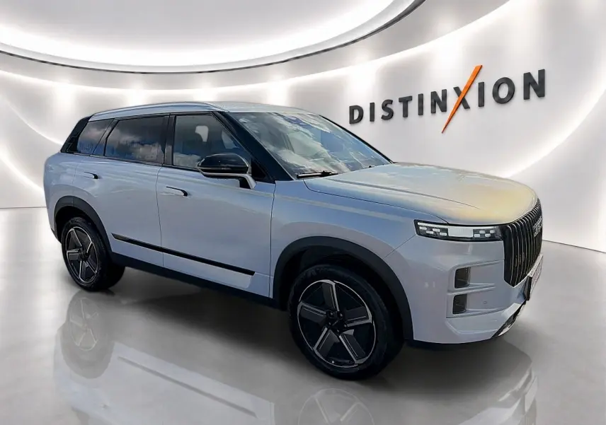 SUV JAECOO J7 gris moonlight vu en 3/4 avant droit dans un showroom lumineux avec jantes alu noires.