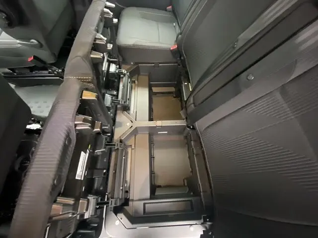 Vue intérieure du Renault Trafic cabine approfondie 2025, montrant l'espace sous les sièges arrière noirs avec trois sièges indépendants.