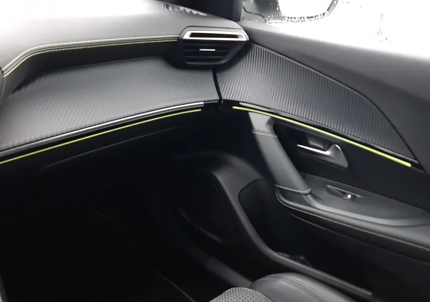 Intérieur côté passager du Peugeot 2008 2023, avec tableau de bord noir texturé et surpiqûres vertes, siège tissu et cuir.