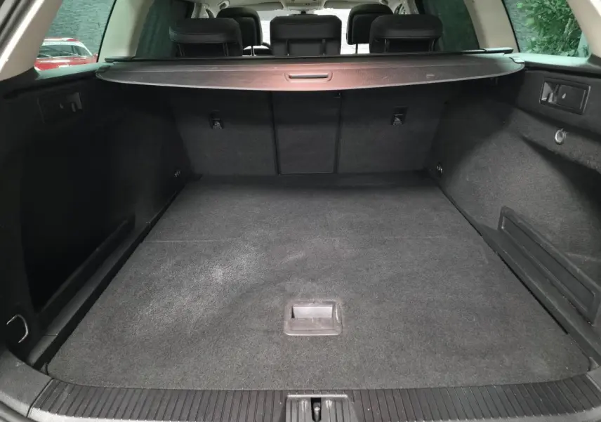 Coffre spacieux de Volkswagen Passat SW gris vu de l'arrière avec cache-bagages et banquette arrière noire.