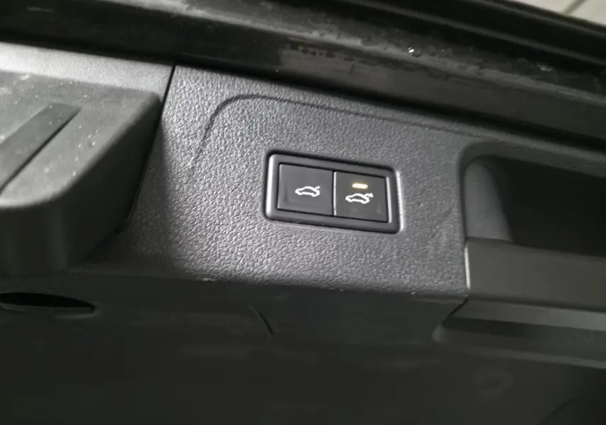 Boutons d'ouverture électrique du coffre et du hayon sur la partie intérieure du coffre d'une Volkswagen Passat SW gris.
