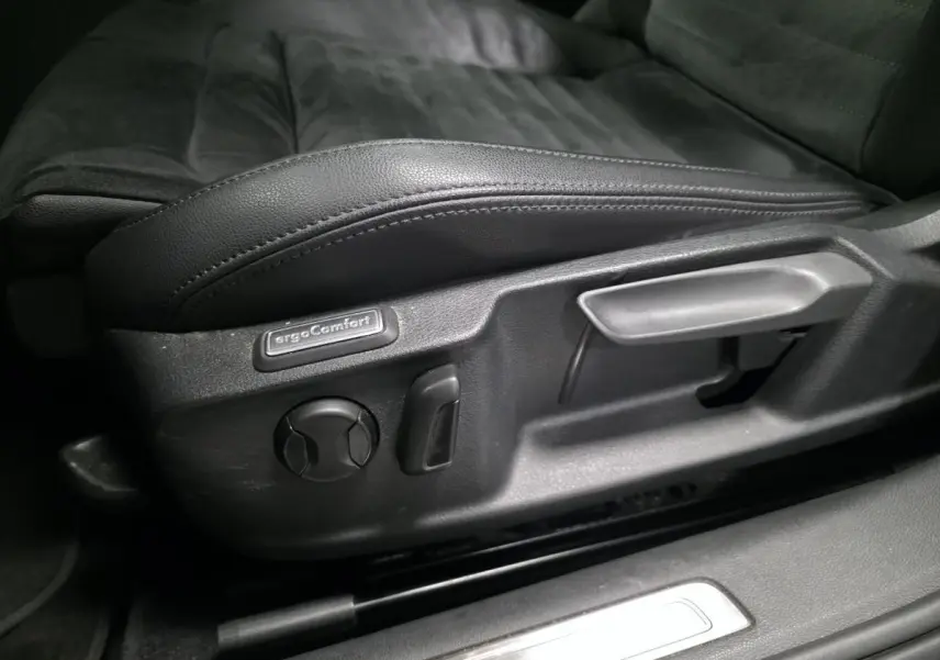Gros plan sur les commandes de réglage du siège conducteur noir en cuir de la Volkswagen Passat SW Carat 2019.
