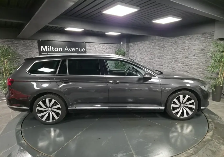 Profil droit d'une Volkswagen Passat SW gris métallisé avec jantes alliage 18 pouces Dartford dans un showroom intérieur.