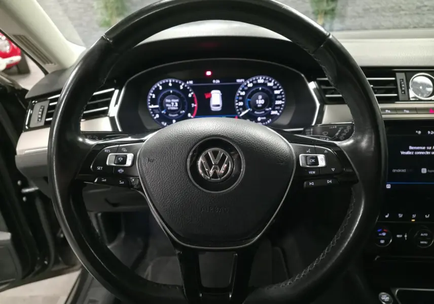 Vue rapprochée du volant en cuir noir multifonction de la Volkswagen Passat SW 2019 avec tableau de bord digital.
