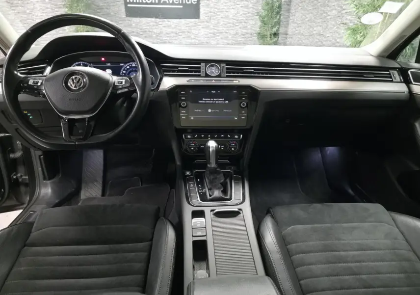 Vue intérieure avant de la Volkswagen Passat SW Carat 2019 avec tableau de bord noir et console centrale équipée d'un levier de vitesses automatique.