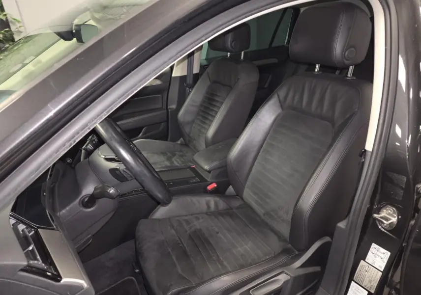 Vue intérieure côté conducteur de la Volkswagen Passat SW 2019 avec sièges en cuir noir et volant multifonction.