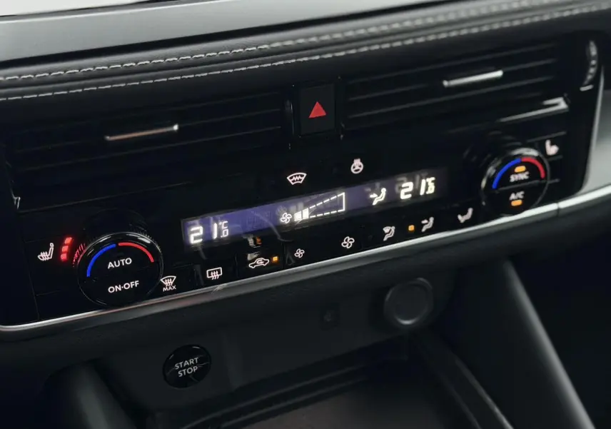 Gros plan sur la console centrale du Nissan Qashqai 2025, montrant les commandes de climatisation automatique bi-zone.