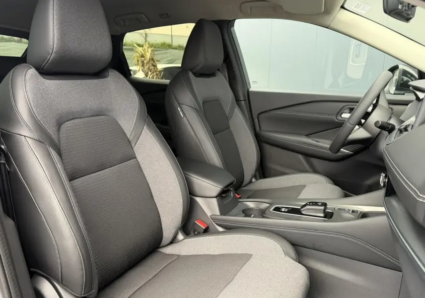 Vue intérieure côté droit du Nissan Qashqai 2025, sièges avant bi-matière gris et noir avec console centrale moderne.