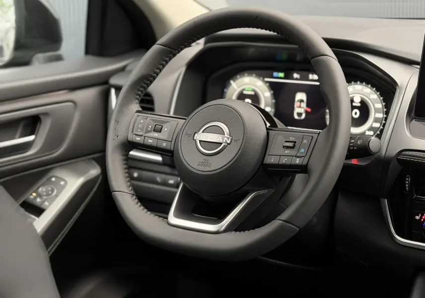Vue rapprochée du volant cuir noir et du tableau de bord numérique du Nissan Qashqai III gris Squale, version 2025.