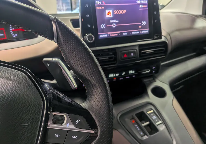 Intérieur du Peugeot Rifter 2024 BlueHDi, vue rapprochée du volant à gauche et de l’écran tactile central affichant une radio.