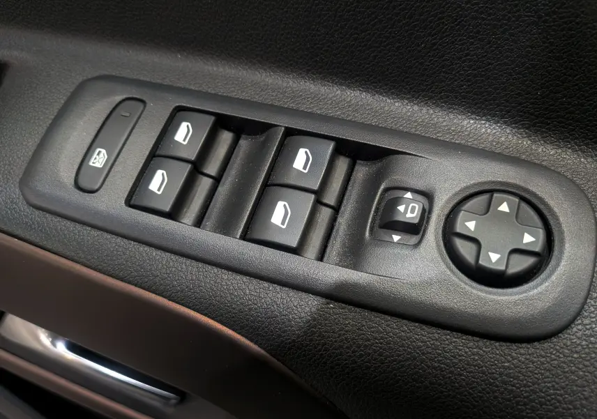 Gros plan sur les commandes de lève-vitres et réglages des rétroviseurs côté conducteur du Peugeot Rifter gris Artense 2024.