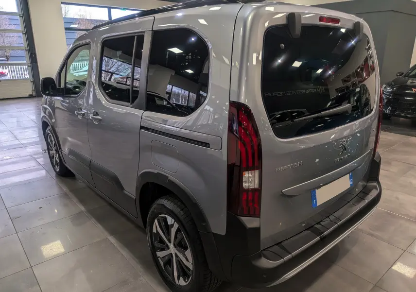 Vue 3/4 arrière droite du Peugeot Rifter 2024 gris Artense avec vitres teintées et feux arrière verticaux distinctifs.