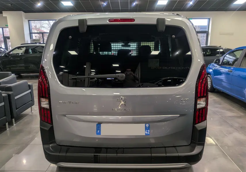 Vue arrière du Peugeot Rifter 2024 gris Artense, avec feux verticaux rouges et lunette arrière teintée en showroom.