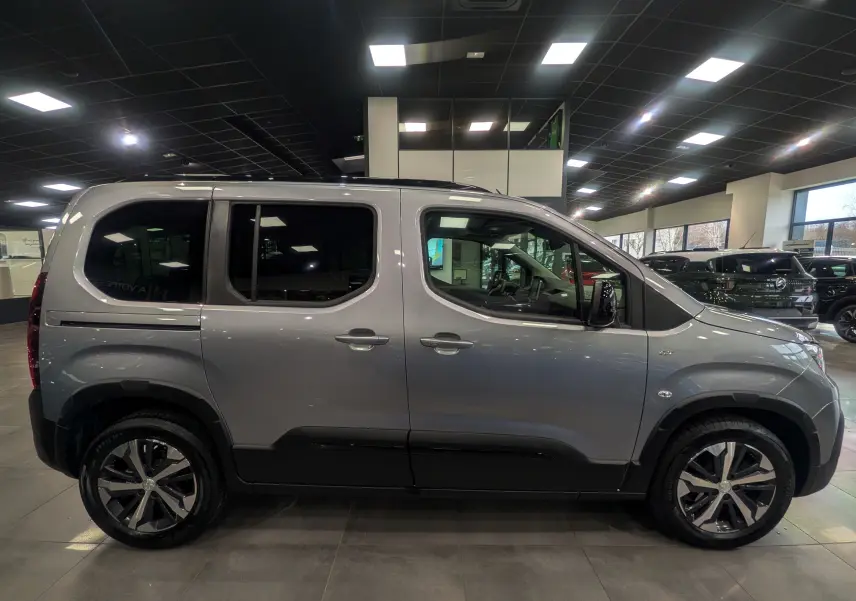 Vue latérale droite du Peugeot Rifter 2024 gris Artense, soulignant ses jantes bi-ton et ses vitres teintées.