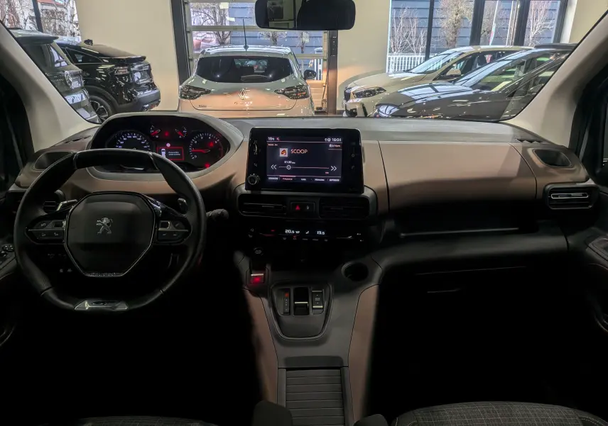 Vue intérieure avant du Peugeot Rifter 2024, tableau de bord moderne avec écran tactile central et volant compact noir.