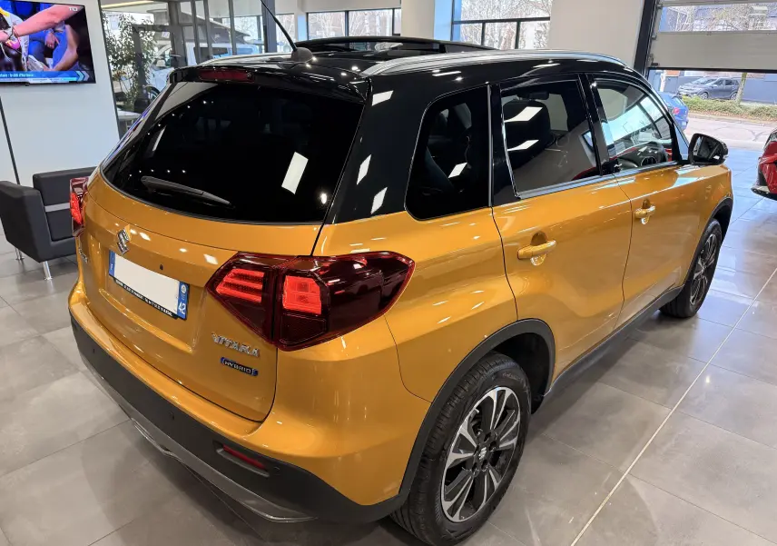 Vue 3/4 arrière droite du Suzuki Vitara 1.5 Dualjet Hybrid 2023 jaune avec toit noir et jantes alliage biton.