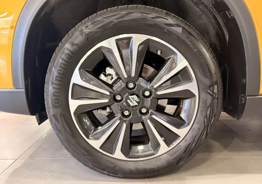 Gros plan sur la roue avant droite du Suzuki Vitara jaune toit noir, mettant en valeur la jante alliage bicolore et le pneu Continental.