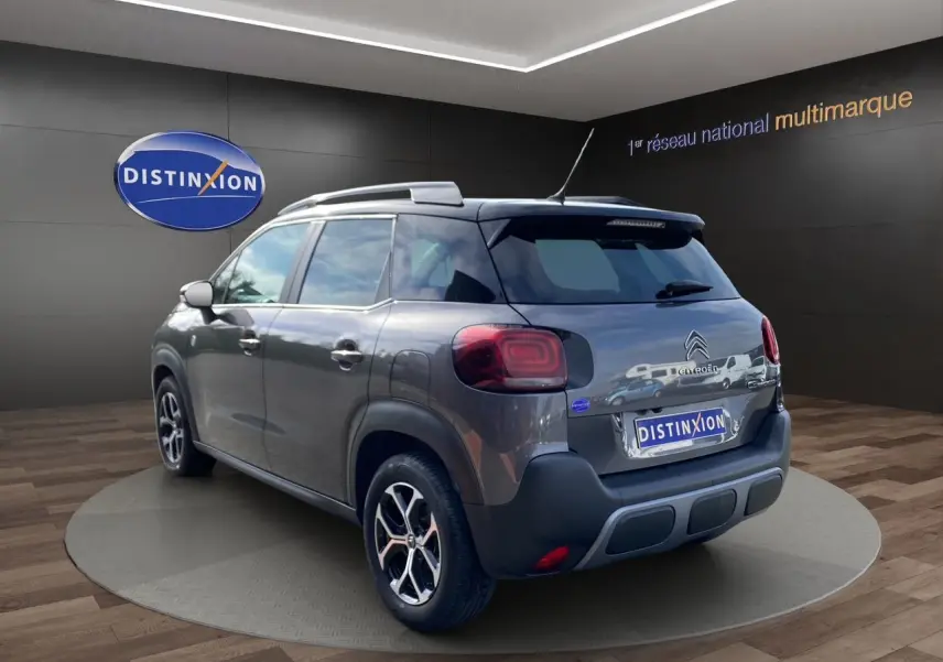 Vue 3/4 arrière droite d'un Citroën C3 Aircross gris platinium avec jantes alliage et caméra de recul visible.