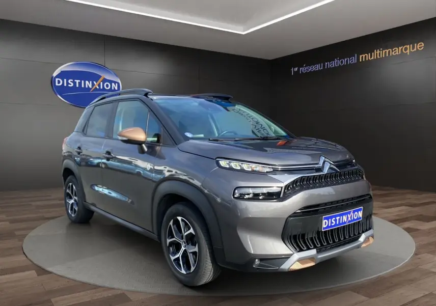 Vue 3/4 avant droit d'un Citroën C3 Aircross gris platinium avec détails cuivrés sur les rétroviseurs et la calandre.