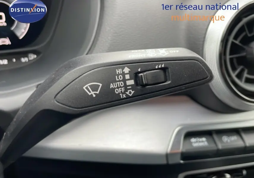 Gros plan sur la commande d’essuie-glace à gauche du volant dans l’Audi Q2 argent rose métal, tableau de bord en arrière-plan.