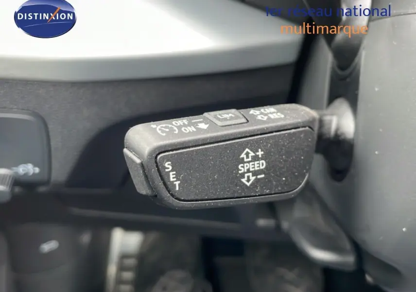 Gros plan sur la commande de régulateur de vitesse du volant d’un Audi Q2 argent rose métal, intérieur noir.