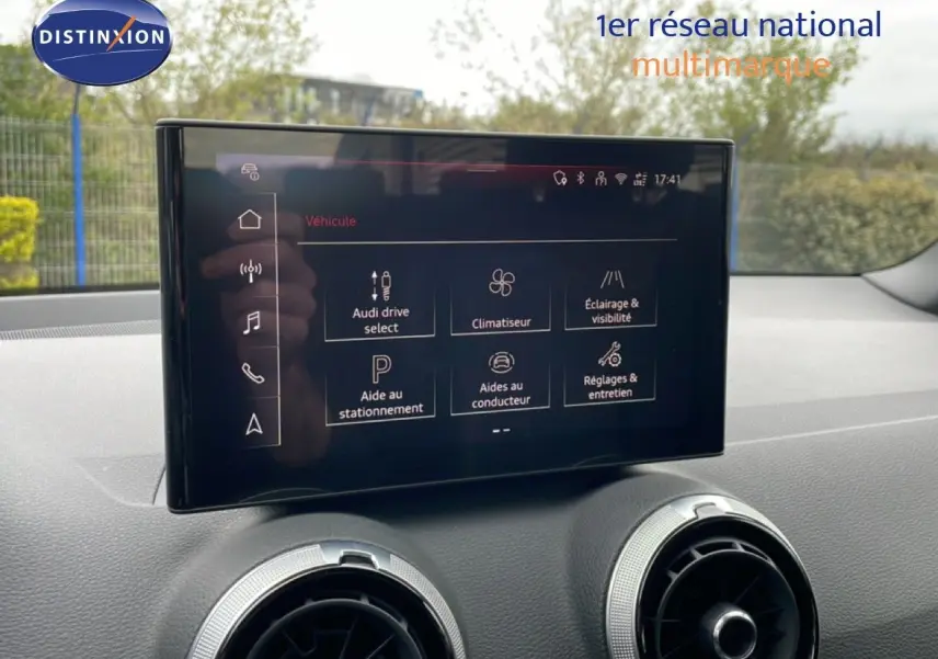 Écran tactile central de l'Audi Q2 2025 affichant les options de conduite et d'assistance, intérieur noir visible.