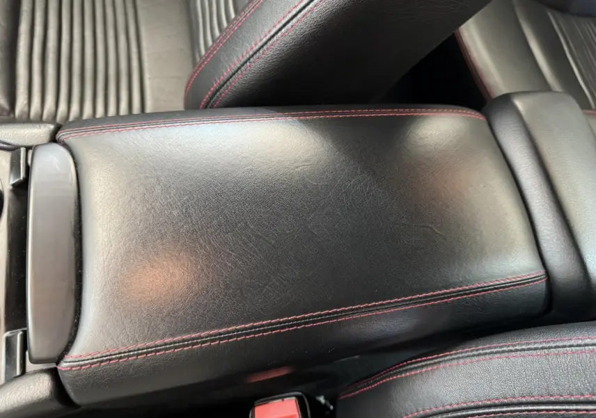 Gros plan sur l'accoudoir central en cuir noir avec surpiqûres rouges dans l'habitacle de la Maserati Granturismo S 4.7.