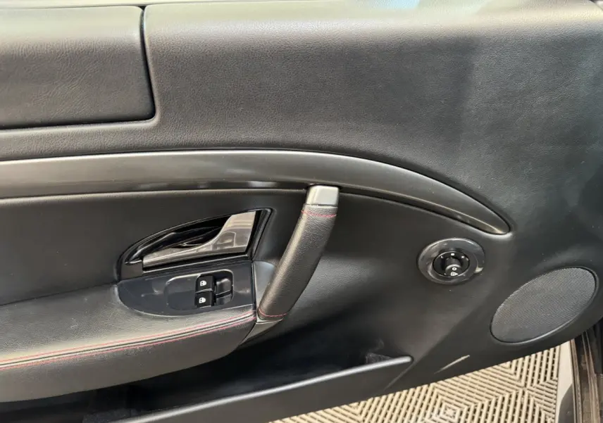 Vue rapprochée de la porte intérieure côté gauche d'une Maserati Granturismo S 4.7 gris foncé avec surpiqûres rouges.