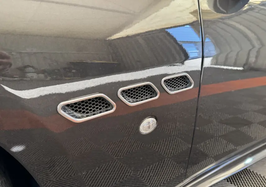 Gros plan sur les trois ouïes latérales chromées et la couleur gris foncé de la porte d'une Maserati Granturismo S 4.7.