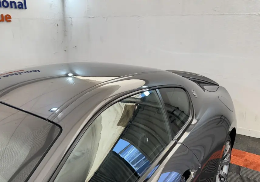Vue 3/4 arrière droite d'une Maserati Granturismo S 4.7 gris foncé avec spoiler de coffre et jantes argentées.