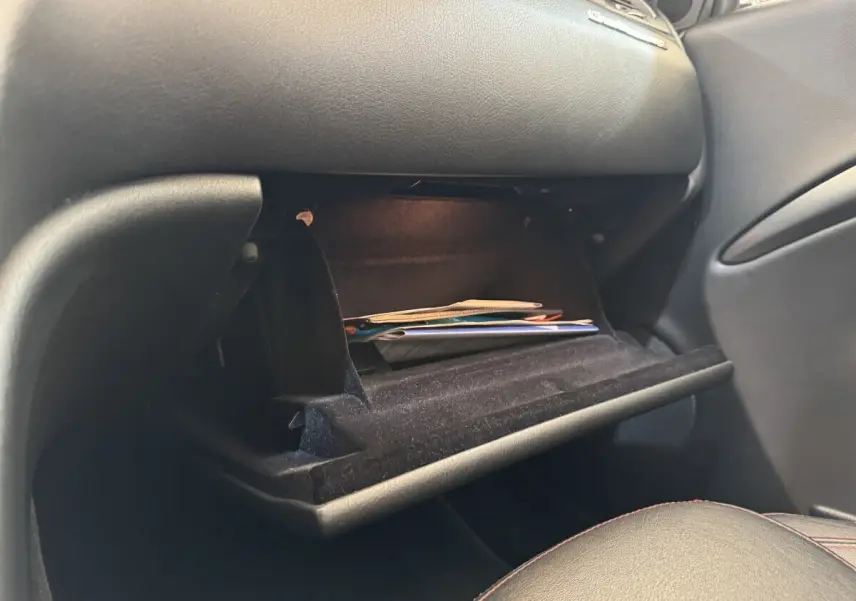 Gant de boîte à gants ouvert côté passager dans l’habitacle noir d’une Maserati Granturismo S 4.7 gris foncé 2010.