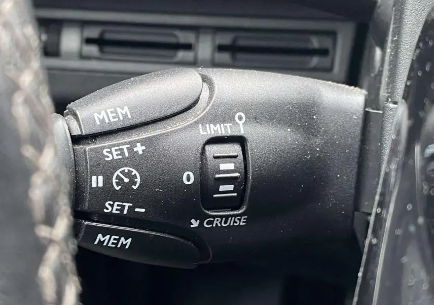 Gros plan sur la commande de régulateur de vitesse du Peugeot 3008, bouton noir avec inscriptions blanches.