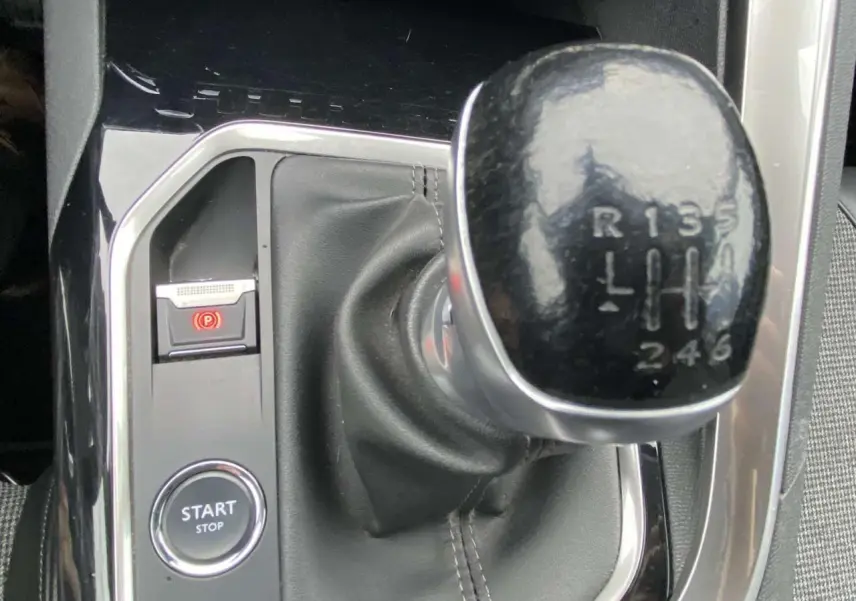 Gros plan sur le levier de vitesses manuelle noir et la console centrale brillante du Peugeot 3008 marron foncé.