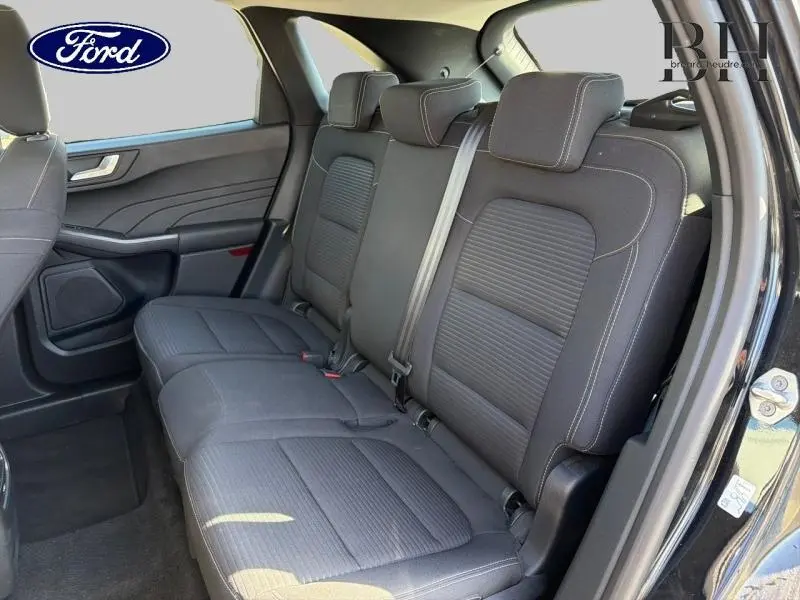 Vue intérieure sur la banquette arrière noire du Ford Kuga 2023, avec ceintures et appuie-têtes visibles côté droit.