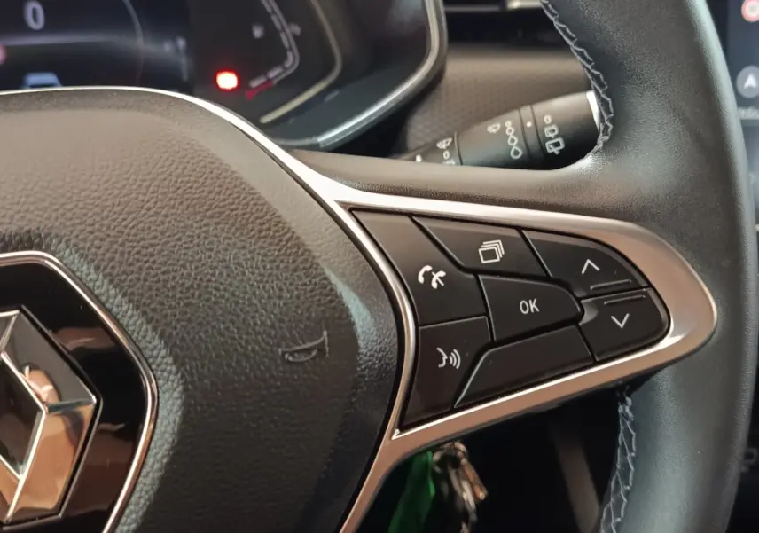 Gros plan sur le volant cuir de la Renault Clio Business E-TECH 140 2021, avec commandes multifonctions visibles.
