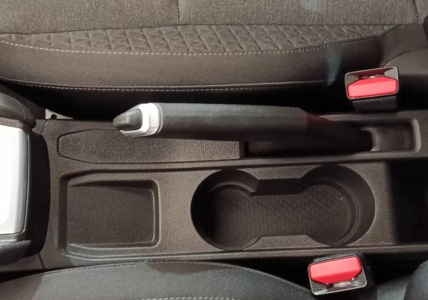 Vue plongeante sur la console centrale noire de la Renault Clio Business E-TECH 140 avec frein à main manuel et porte-gobelets.