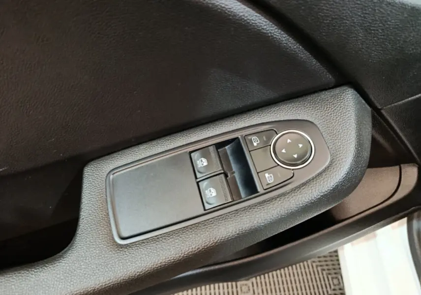 Commande des vitres électriques et réglage des rétroviseurs sur la porte côté conducteur d'une Renault Clio blanche.