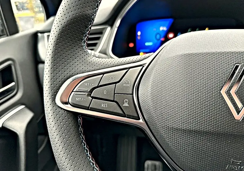 Gros plan sur le volant perforé côté gauche de la Renault Symbioz 2026 bleu iron avec commandes multifonctions.