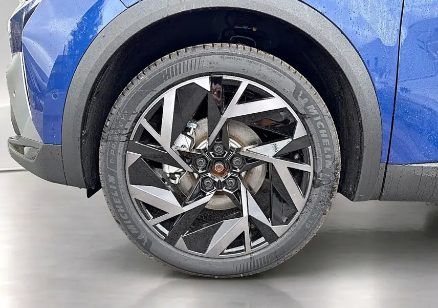 Gros plan sur la roue avant gauche avec jante alu noire et argentée du Renault Symbioz bleu iron.