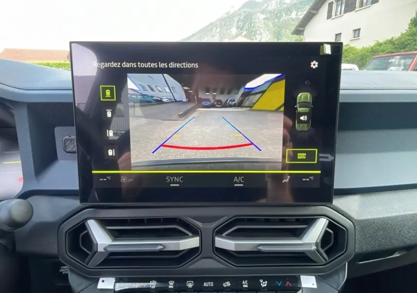 Vue intérieure du tableau de bord du Dacia Bigster 2025 avec écran de caméra de recul et aérateurs hexagonaux noirs.