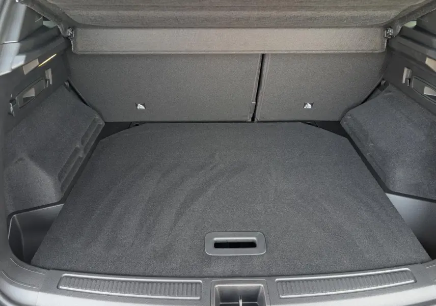 Coffre ouvert vu de l'arrière d'un Renault Austral gris métallisé, avec plancher de coffre plat et tapis noir.