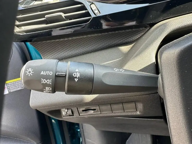Gros plan sur la commande des phares et clignotants à gauche du volant dans une Peugeot 308 bleu 2025.